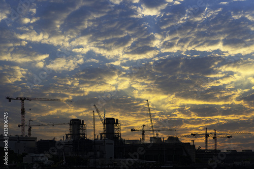 Industrial construction cranes and building silhouettes at sunrise..