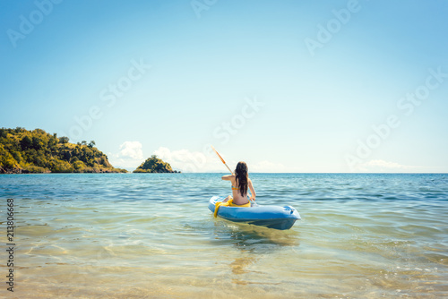 Woman paddling on a kayak on sea in clear water enjoying the summer