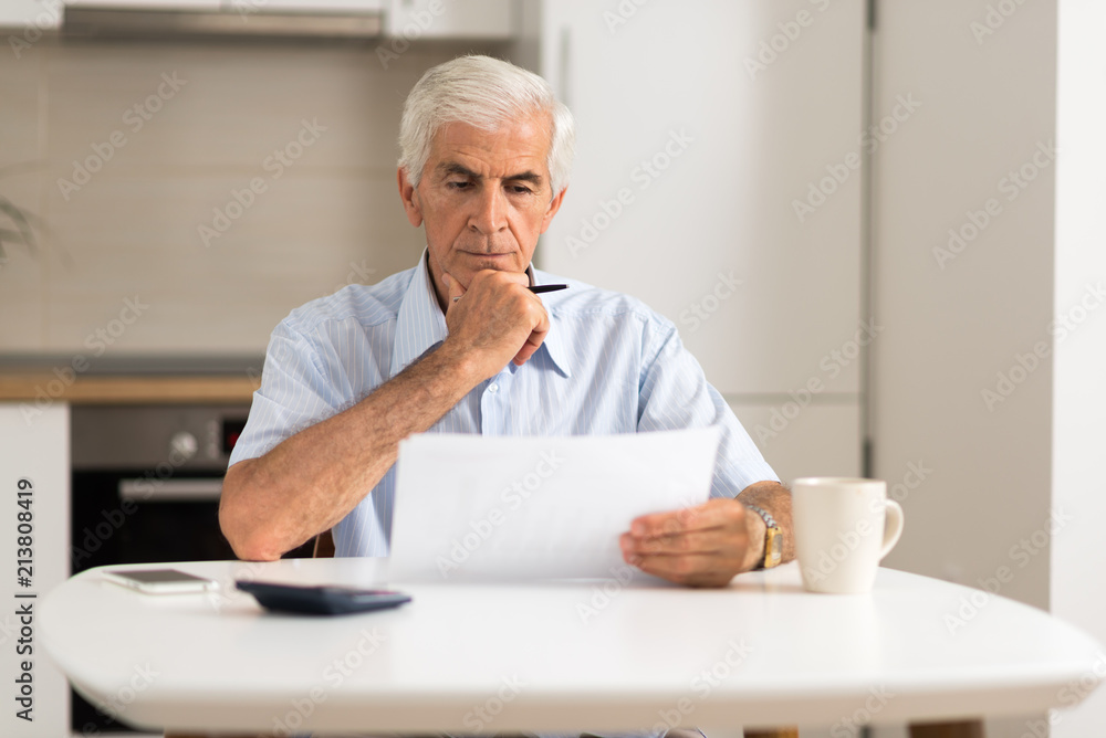 Elderly man sitting at home and calculating bills and taxes. Elderly man sitting at home and calculating bills and taxes.