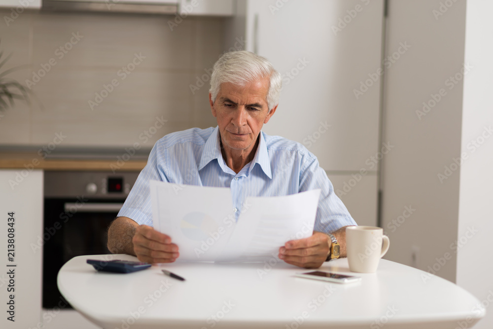 Elderly man sitting at home and calculating bills and taxes. Elderly man sitting at home and calculating bills and taxes.