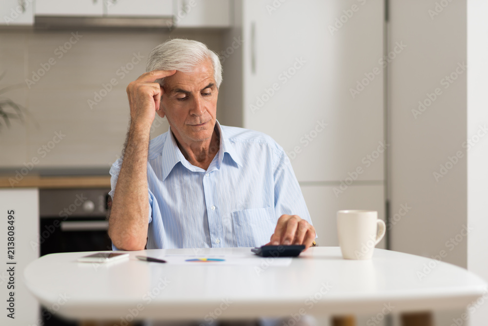 Elderly man sitting at home and calculating bills and taxes. Elderly man sitting at home and calculating bills and taxes.