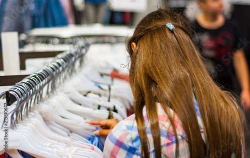 Teenage girl shopping for clothes inside Clothing store at shopping center