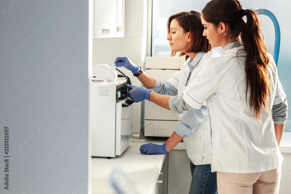 Female dentists in dental office .They cleans equipment for next working day.Using autoclave. Female dentists in dental office .They cleans equipment for next working day.Using autoclave.