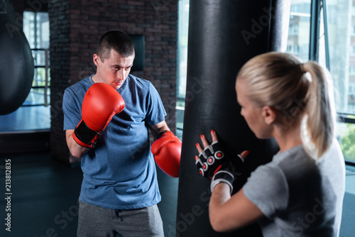 Blue shirt. Dark-haired professional boxer wearing sports blue shirt working with his trainer © zinkevych