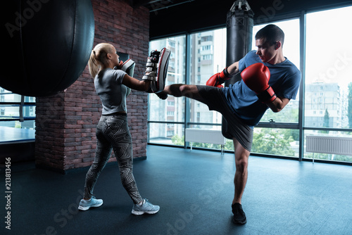Gym with view. Dark-haired professional skillful boxer working out in gym with city view