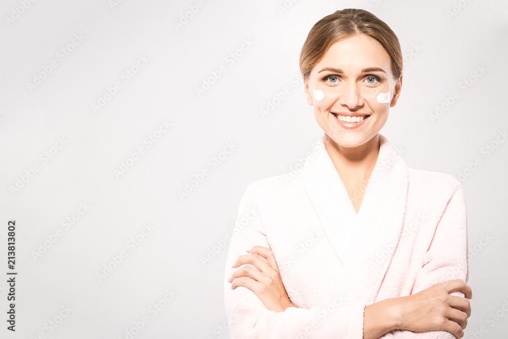 Portrait of young beautiful woman smiling while taking some facial cream isolated on white background with copy space. Portrait of young beautiful woman smiling while taking some facial cream isolated on white background with copy space.