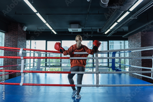 Boxing ring. Professional boxer standing in boxing ring while planning her great sport career