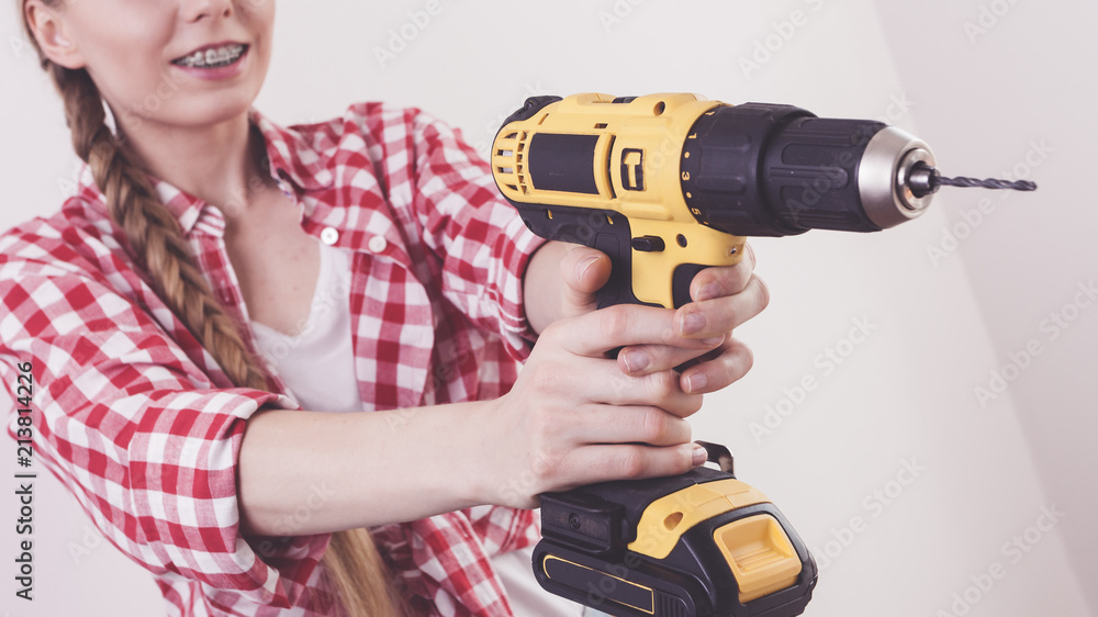 Woman using drill on wall Woman using drill on wall