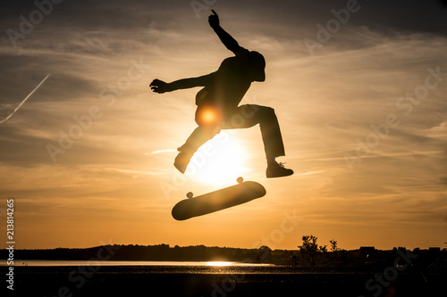 Skater make trick kickflip against the beautiful orange sunset photo