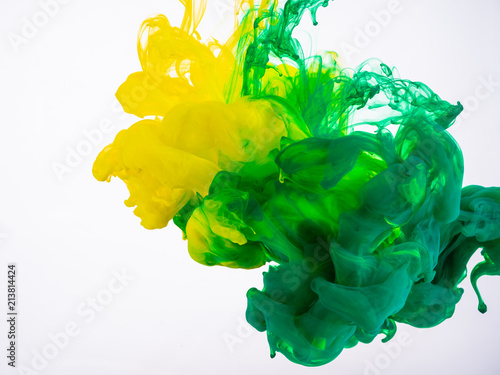 Yellow and green acrylic paint make an abstract explosion under water. Two ink colours mixing in liquid, isolated on white background. Yellow-green acrylic ink explosion under water