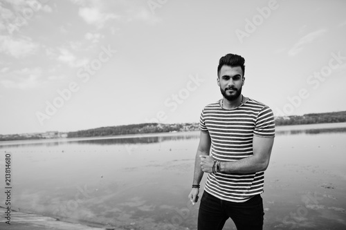 Handsome tall arabian beard man model at stripped shirt posed outdoor. Fashionable arab guy.