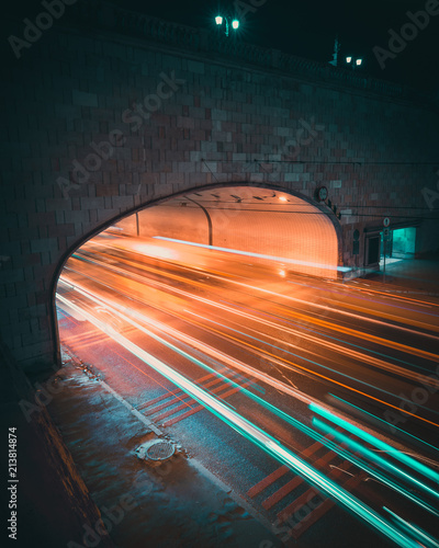 Traffic colorful light trails of cars driving in and out of a tunnel at night.