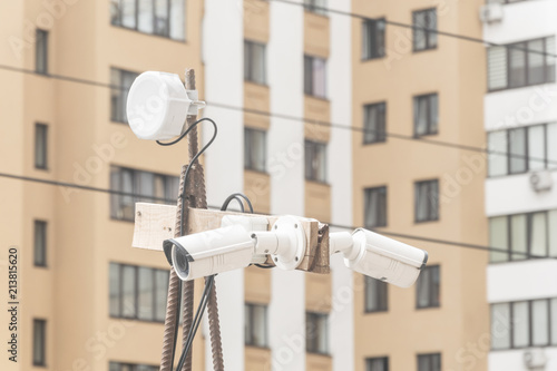 Security cameras on a pole on the background of a residential building.