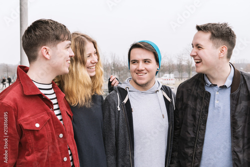 group of four young teenage friends talking and laughing together, candid real people
