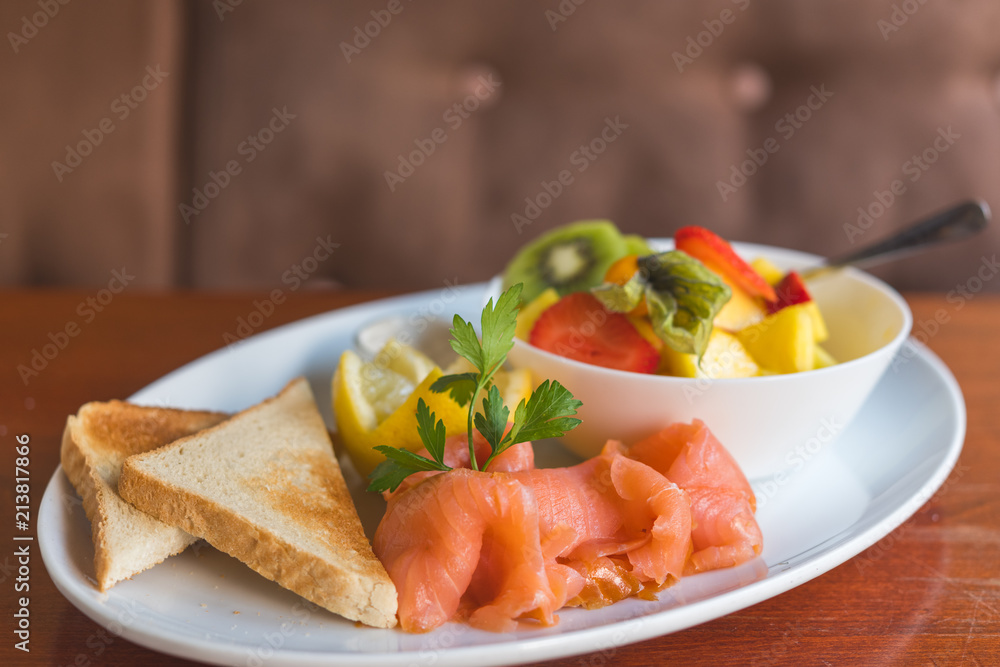 Geräucherter Lachs mit Toast und frischem Obstsalat in einem Cafe zum Frühstück serviert 