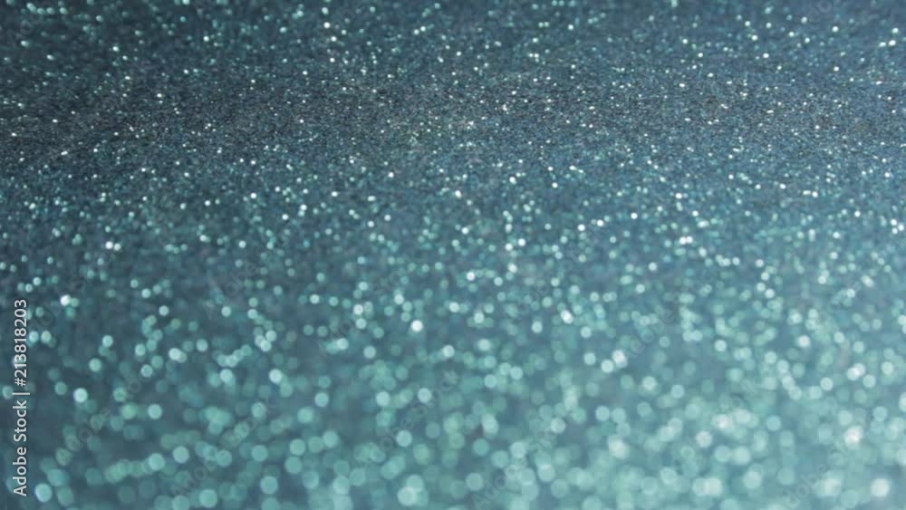 Rack focus closeup shot of black and blue glitter. Shiny speckles twinkling under strong light. Selective focus combined with bokeh. Dreamy, magical, mystery concept. Rack focus closeup shot of black and blue glitter. Shiny speckles twinkling under strong light. Selective focus combined with bokeh. Dreamy, magical, mystery concept.