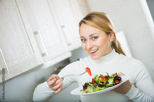 Cheerful blond girl eating salad