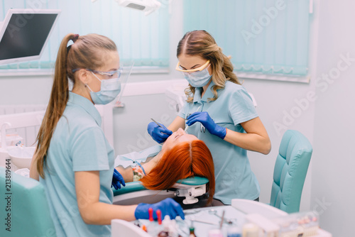 young woman dentist treats teeth to her patient
