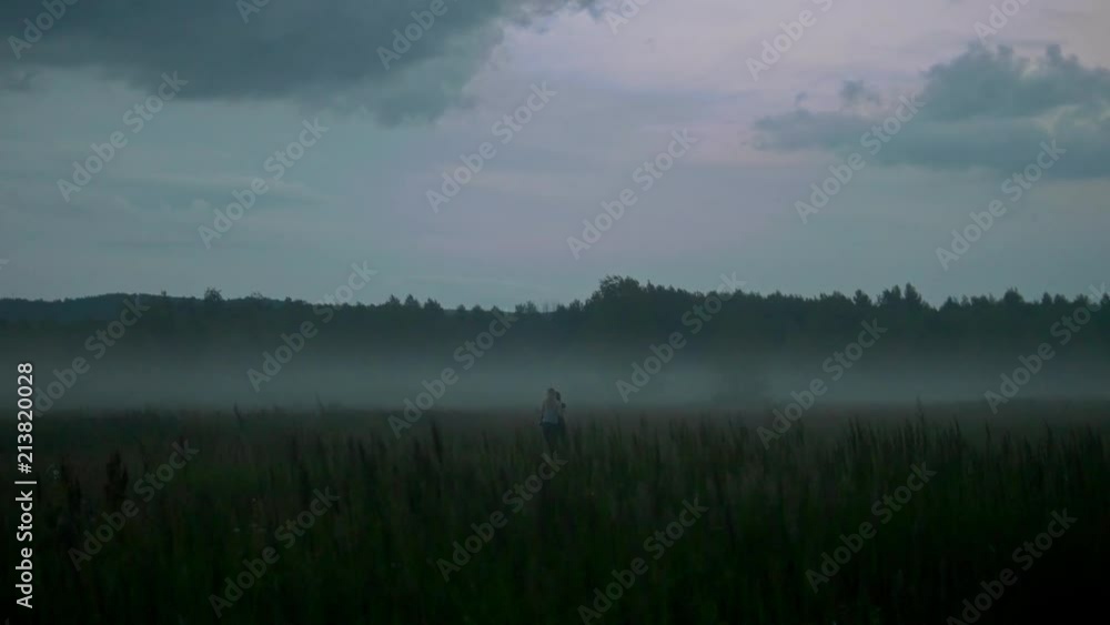 Two young women walks through the field in the fog Two young women walks through the field in the fog