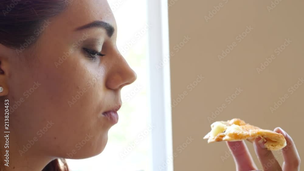 Young pretty girl closeup eat a piece of pizza in fast food restaurant pizzeria Young pretty girl closeup eat a piece of pizza in fast food restaurant pizzeria