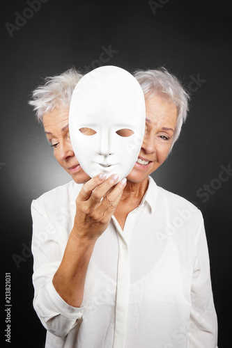 Fotografia older woman hiding happy and sad face behind mask, concept for manic depression