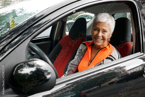 Photography happy smiling mature woman driver in her small compact car