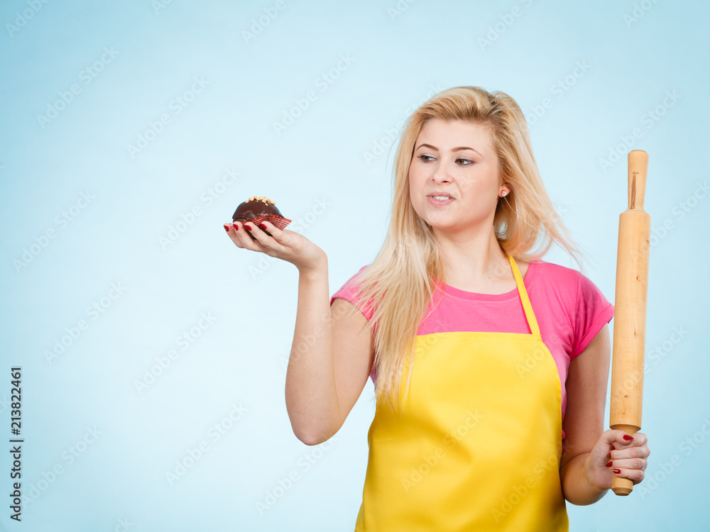 Fototapeta premium Woman holding cupcake and rolling pin wearing apron