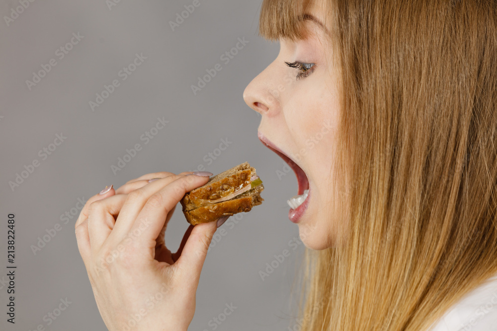 Woman eating sandwich, taking bite Woman eating sandwich, taking bite