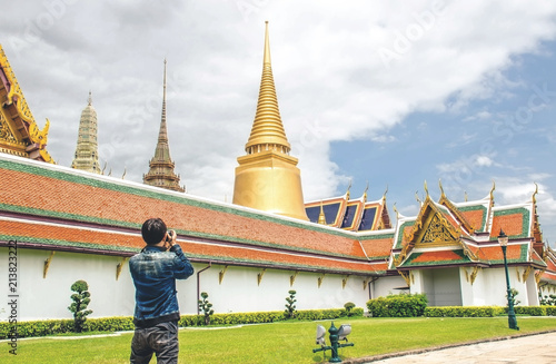 Young Asian traveling backpacker taking photos in Wat Phra Kaew in Bangkok, Thailand