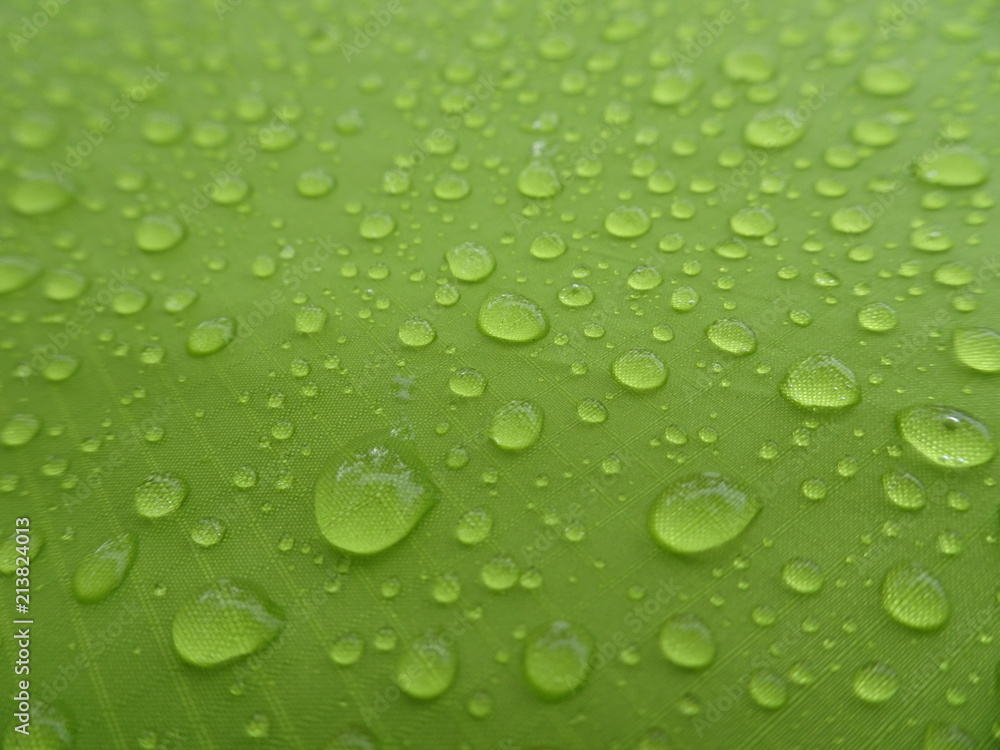 Texture: a drop of water on a green fabric. Water-repellent effect. Waterproof textile