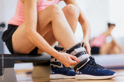 Woman at gym putting ankle weights   photo