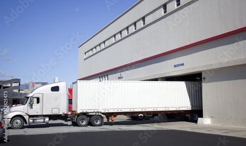 Semi truck with trailer backed into warehouse loading dock. © Noel