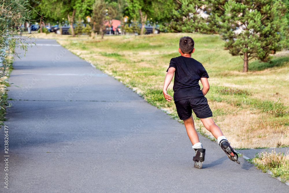 Sporting, athletic boy rollerscating in park alley on summer day Sporting, athletic boy rollerscating in park alley on summer day