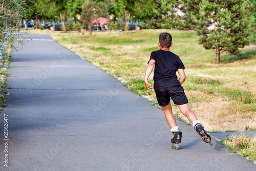 Sporting, athletic boy rollerscating in park alley on summer day © Marina