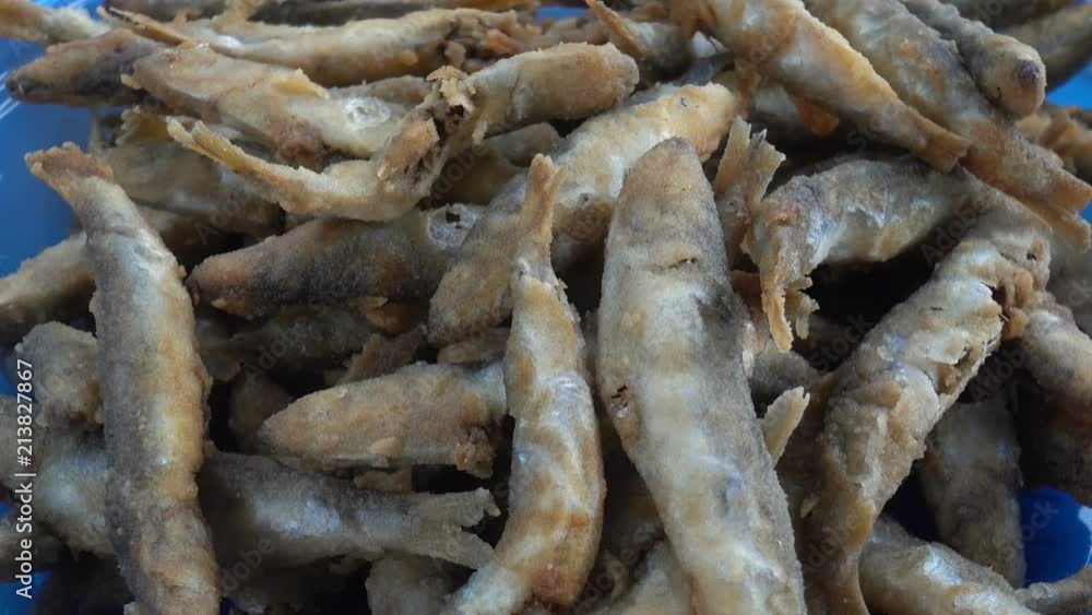 Heap of fried sprat in a blue plate on a table. Traditional fish dish. HD video Heap of fried sprat in a blue plate on a table. Traditional fish dish. HD video