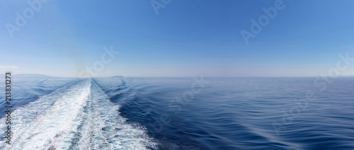 Mediterranean sea. Boat white wake, on blue sea and sky background, view from the ship. Copy space, banner