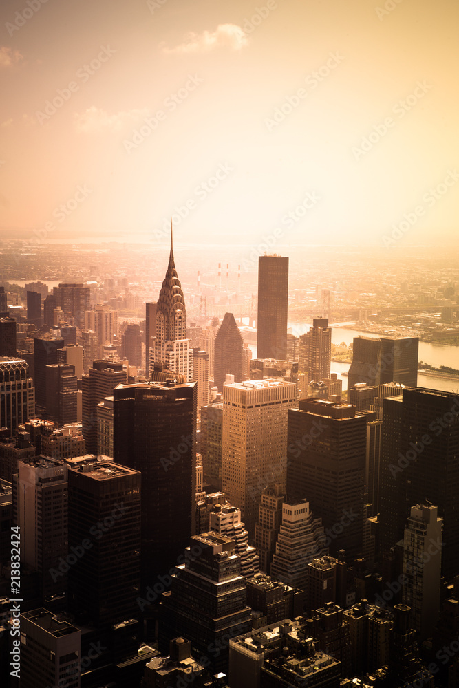 View of buildings across New York City skyline under golden sunset light