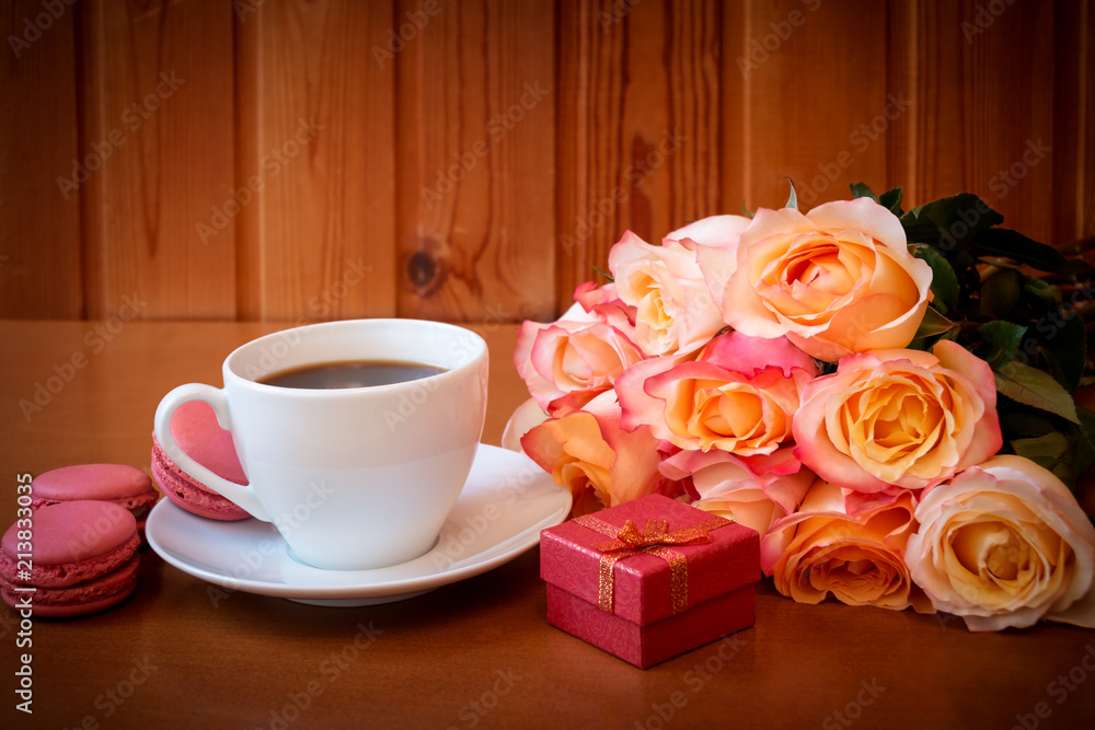 Cup of coffee, bouquet of pink roses flowers and red gift box. Selective focus. Place for text. Cup of coffee, bouquet of pink roses flowers and red gift box. Selective focus. Place for text.