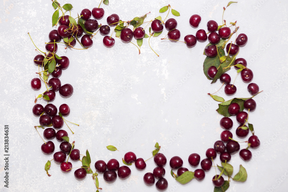 Frame of ripe red cherries on the textured gray background with copy space Frame of ripe red cherries on the textured gray background with copy space