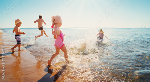Happy kids on vacations at seaside running in the water