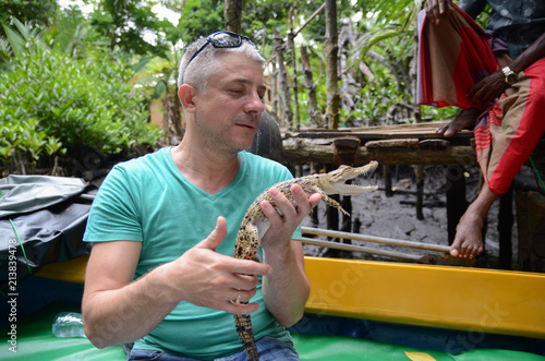A man holds in hands a small crocodile. Jungle of Sri Lanka