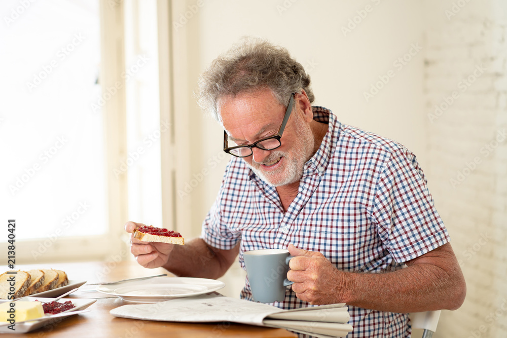 happy old man reading the newspaper while having breakfast happy old man reading the newspaper while having breakfast