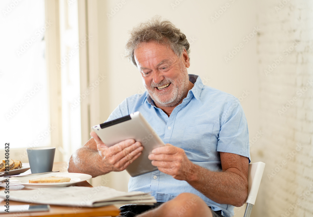 Handsome senior retired old man using tablet with joy while having breakfast at home Handsome senior retired old man using tablet with joy while having breakfast at home