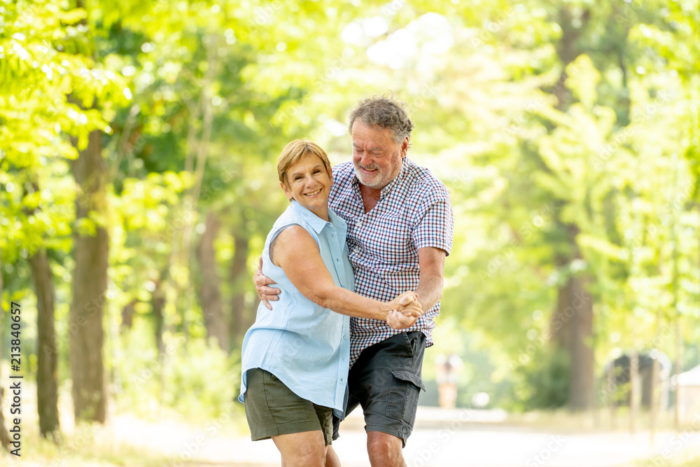 Obraz premium Portrait of a beautiful happy senior couple in love dancing in the park