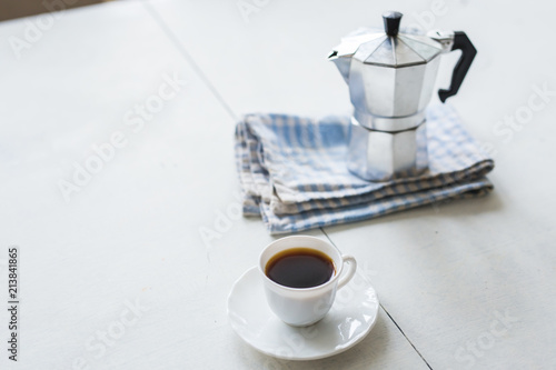 Cup of coffee, coffee kettle on a white table