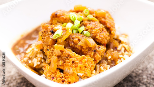 Japanese katsu chicken curry with spring onions and rice in a white bowl