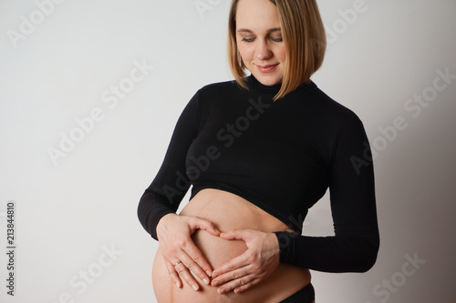 pregnant woman in black holds hands with a heart