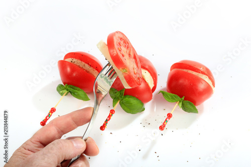 Mozzarella i pomidor nadziany na kolorową wykałaczkę, dłoń z widelcem.