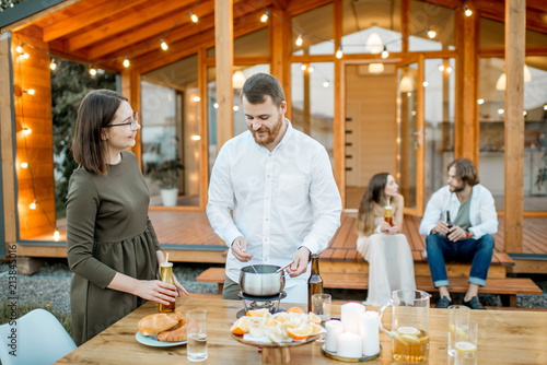 Two lovely couples enjoying evening time on the backyard of the modern wooden house outdoors