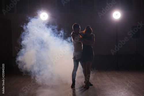 Young couple dancing social danse kizomba or bachata or semba or taraxia in dancing class background